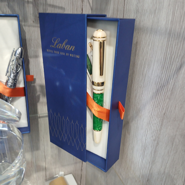 A boxed white fountain pen with gold trim and a green section around the barrel, somewhat closely resembling the ceremonial clothing worn in Mormon temples.  The name on the box reads "Laban".